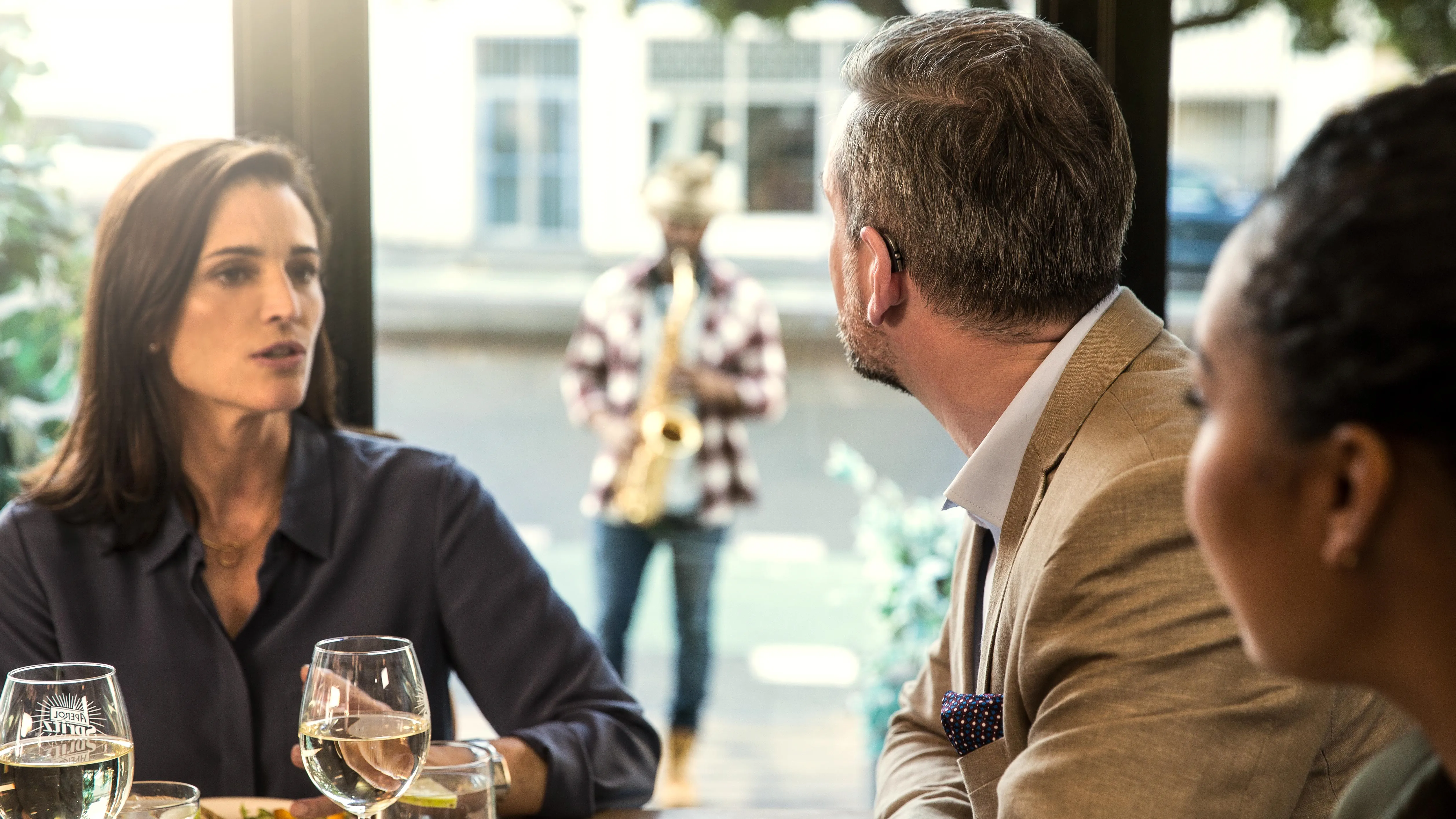 Friends enjoying a cup of coffee at a café using hearing aids
